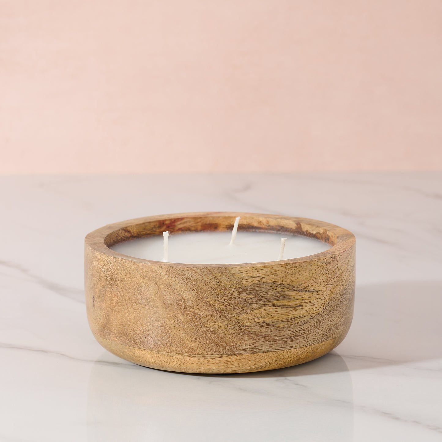 Wooden candle holder with a candle on a light pink background