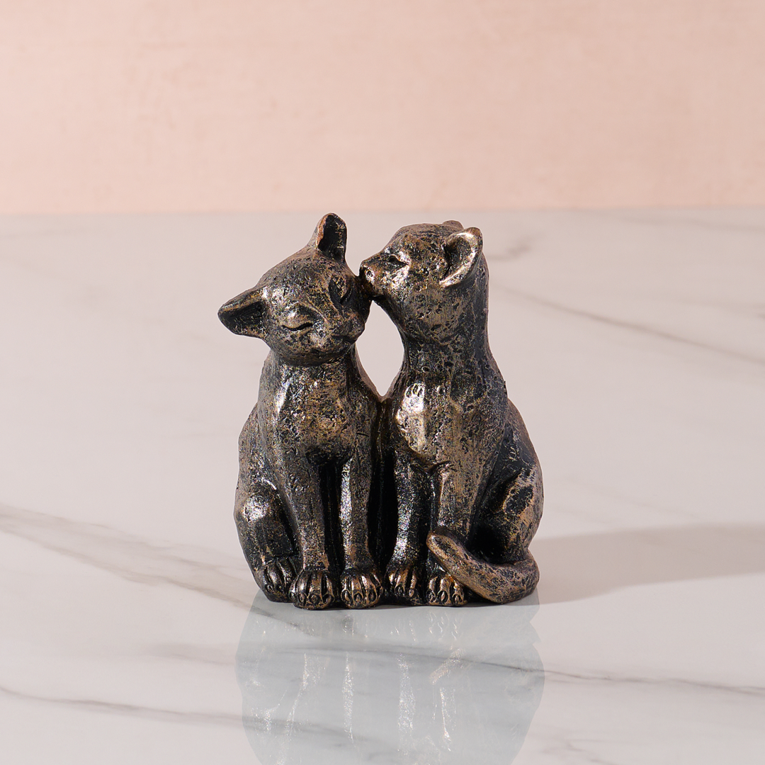 cat ornament with two affectionate cats on a marble base and plain background.