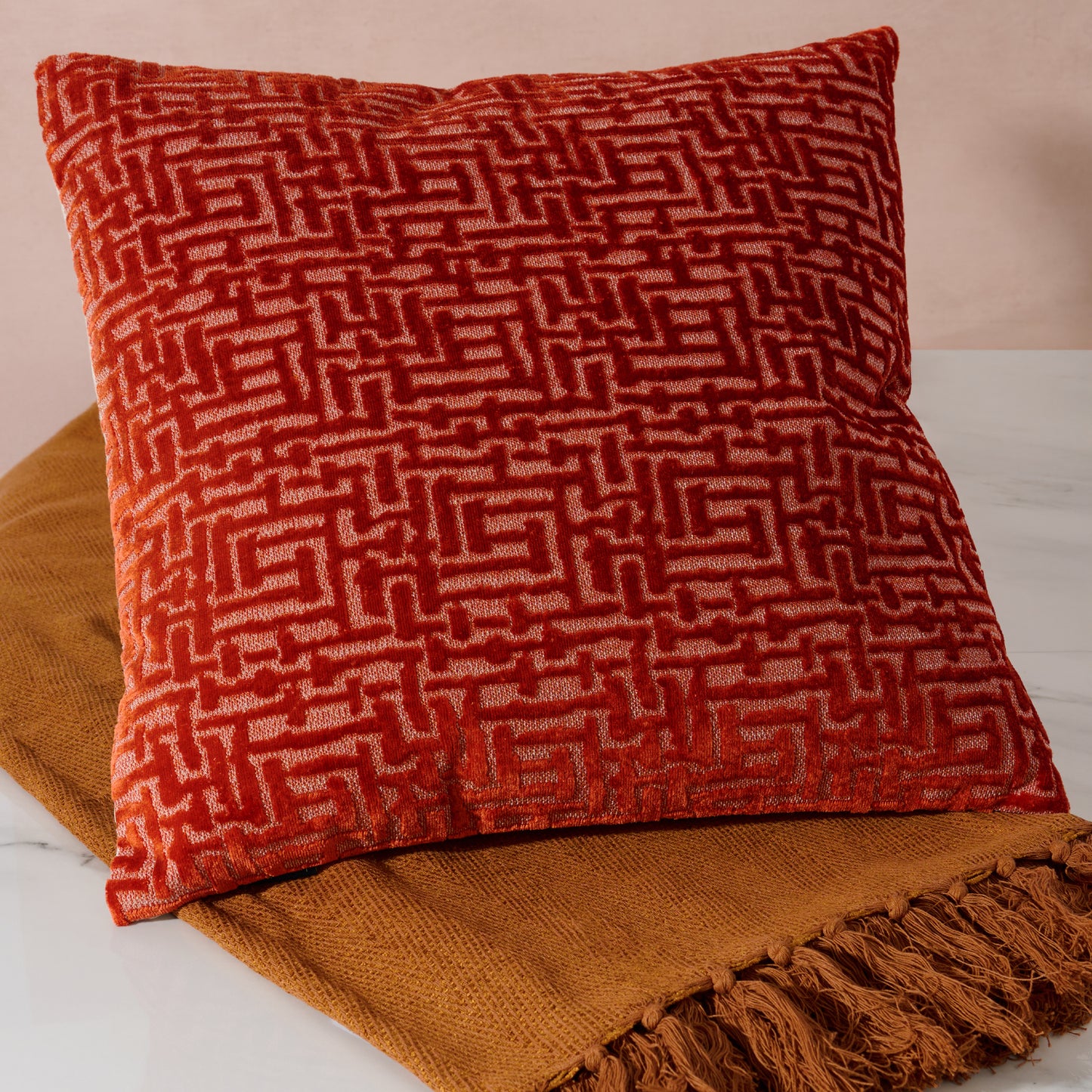 Rust patterned Autumn cushion on a textured surface with a blurred background