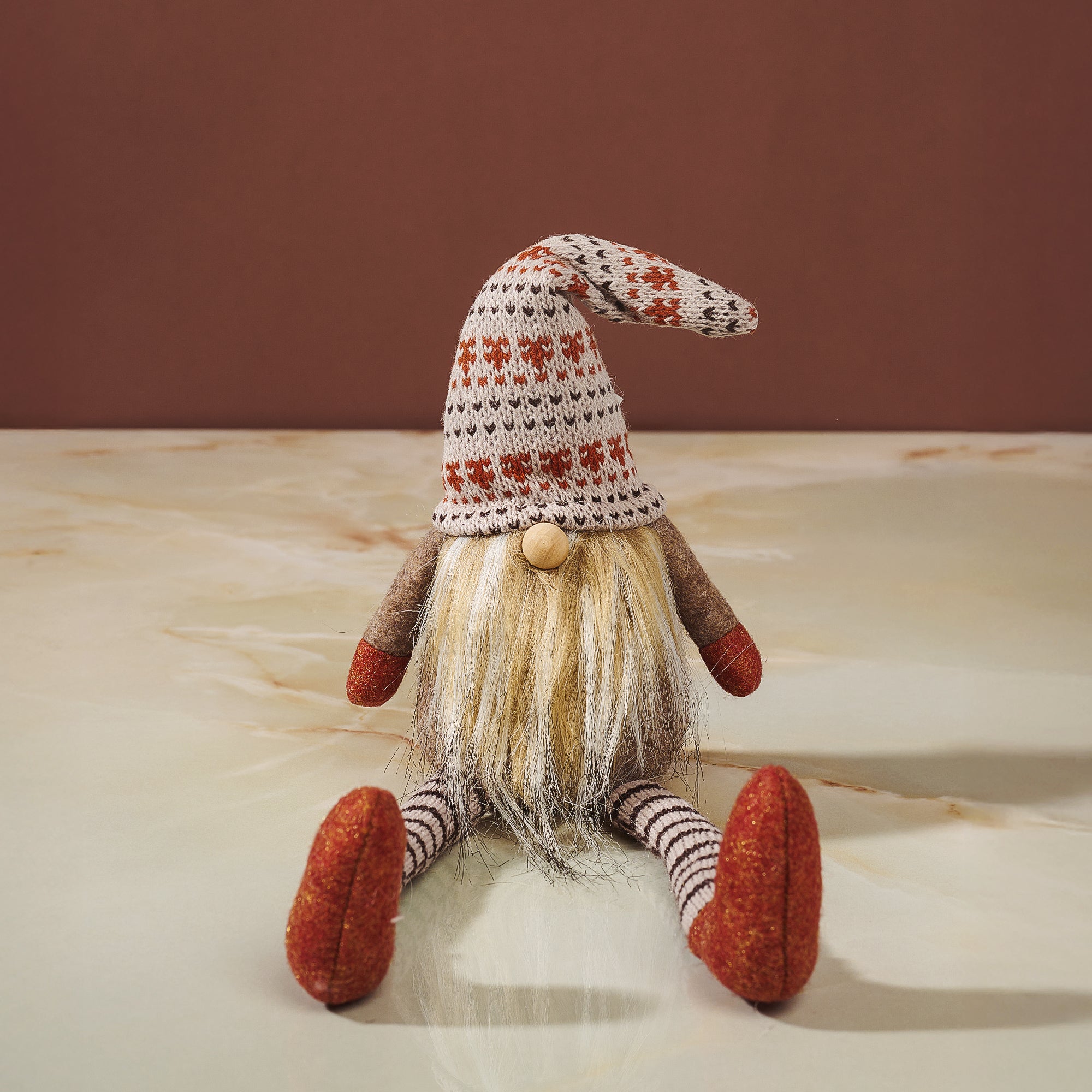 A sitting autumn gonk figurine, with a long beard and a tall hat.