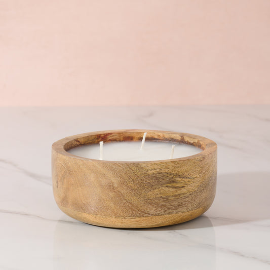Wooden candle holder with a candle on a light pink background
