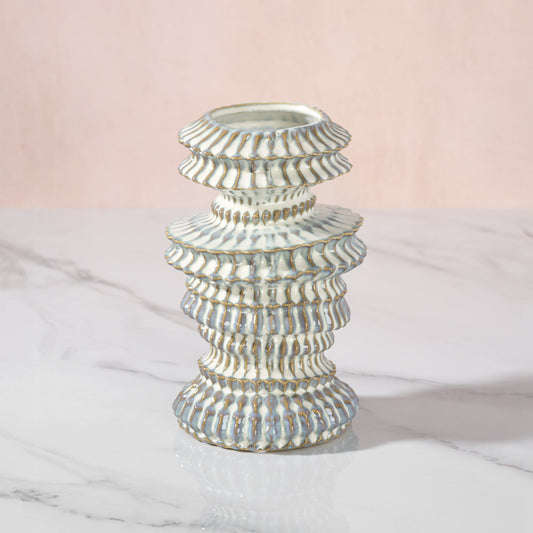 Decorative vase with a ribbed design on a marble surface with a pink gradient background