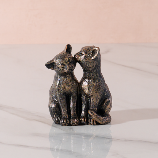 cat ornament with two affectionate cats on a marble base and plain background.